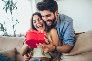A man surprises a woman with a heart-shaped gift box for Valentine's Day